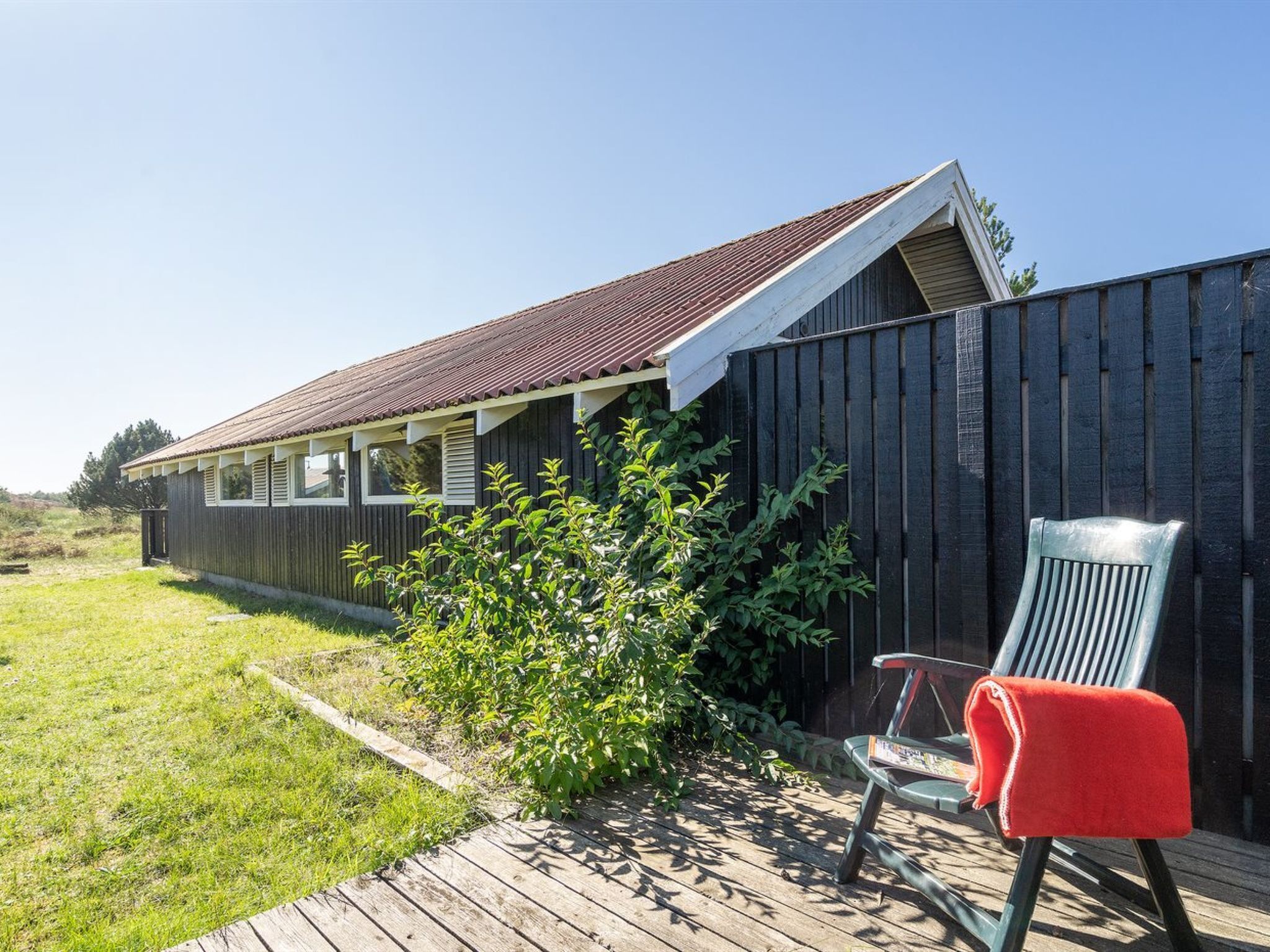 A wooden building with a sloped roof and a fenced yard.