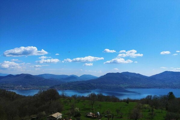 A panoramic view of a lake surrounded by mountains, with a clear sky and scattered clouds. - Romantic House by Lake Maggiore with Garden (Trarego Viggiona)