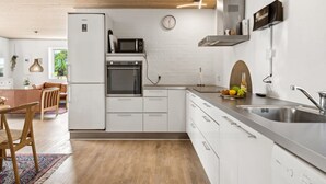 A modern kitchen with white cabinetry, a built-in oven, a microwave, and a stainless steel sink.