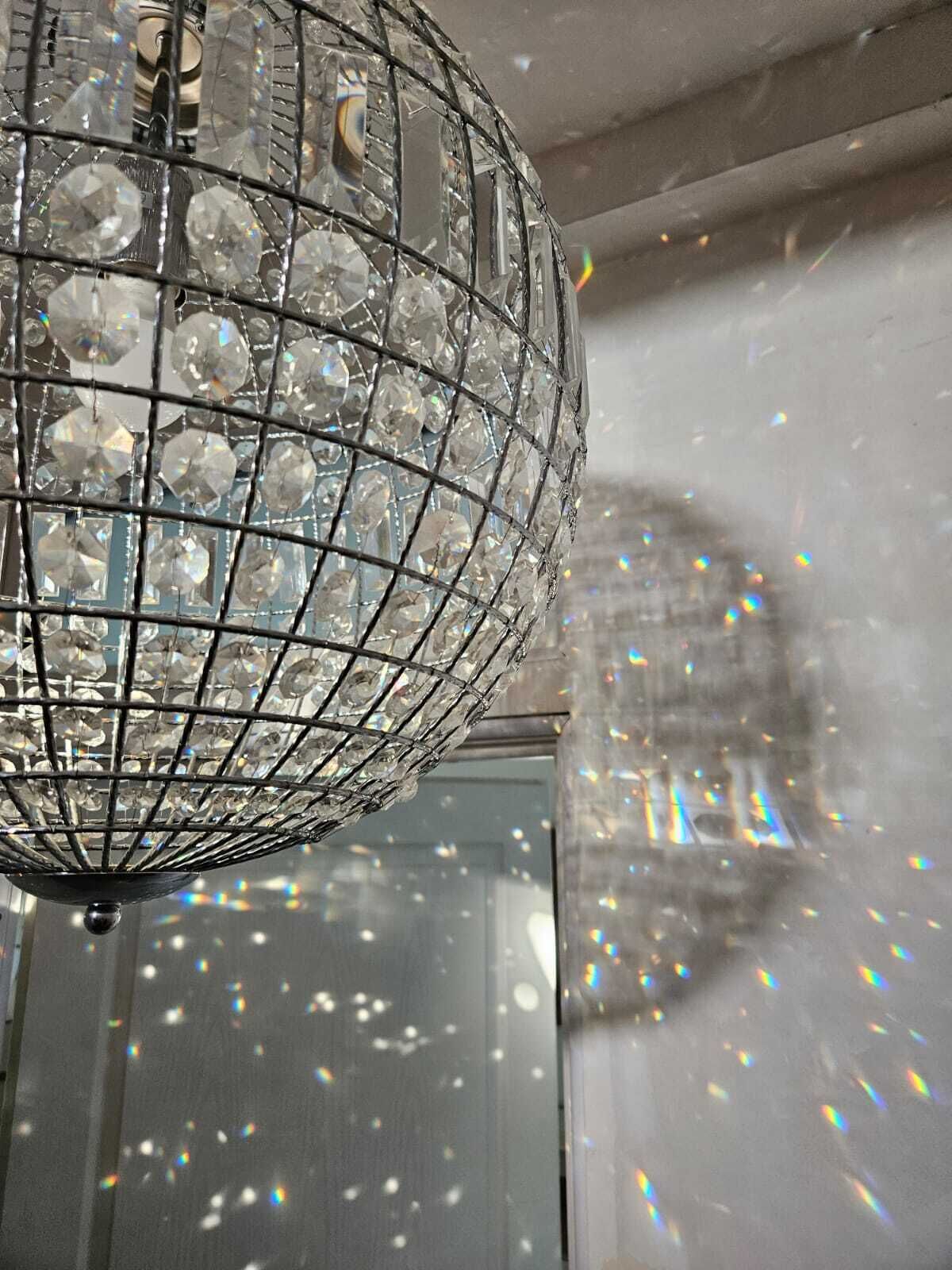A chandelier with a wireframe design and multiple clear crystal elements.