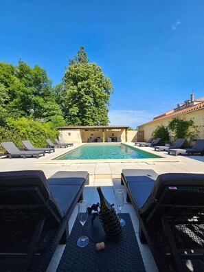 Un espace piscine avec des chaises longues et une bouteille de champagne.