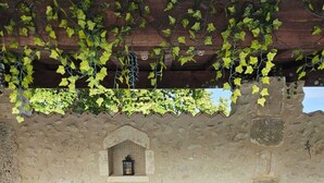 Un patio al aire libre con una mesa y sillas, un muro de piedra y un farol.