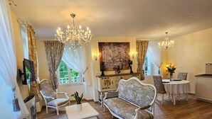 Una sala de estar con un sofá, sillones, una mesa de centro y una araña.