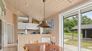 A modern kitchen with wooden cabinets, a dining table with candles, and a view of the outdoors. - "Vojdan" - 600m from the sea by Interhome (Fårevejle)