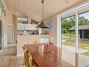 A modern kitchen with wooden cabinets, a dining table with candles, and a view of the outdoors.