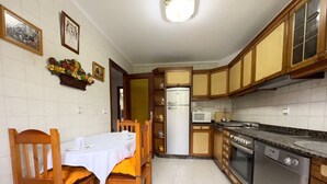 A compact kitchen with wooden cabinets, a built-in oven, and a refrigerator.