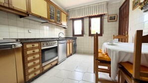 A kitchen with wooden cabinets, a built-in oven, and a dining area with a table and chairs.