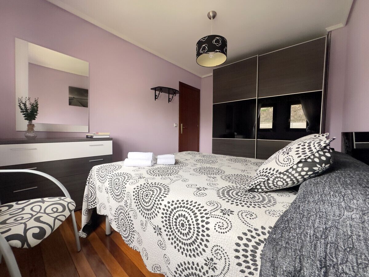 A bedroom with a bed, bedside table, and a mirror.