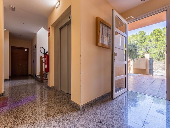 A hallway with a fire extinguisher, a door, and a glass door leading outside. - Apartment Anna by Interhome (L'Ampolla)