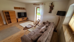 A living room with a sofa, a TV, a wooden cabinet, a small table, and a statue.