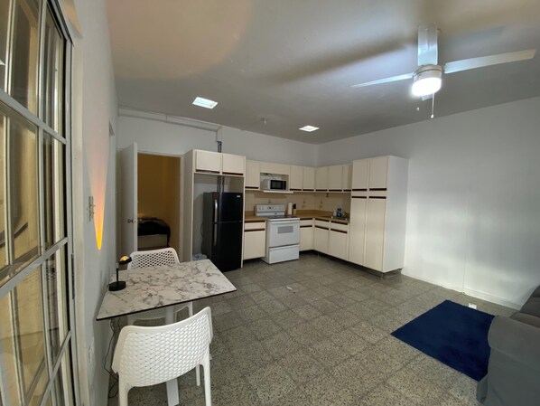 Compact kitchen with a dining area, featuring a stove, microwave, and refrigerator.