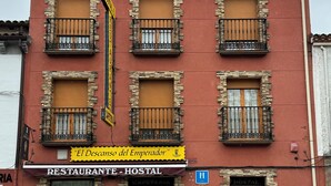 Un bâtiment rouge agrémenté de pierres, doté de nombreux balcons et portant une enseigne indiquant le restaurant et l’auberge « El Descanso del Emperador ».