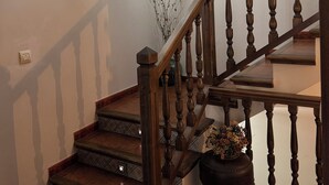 Un escalier avec des balustres en bois et une main courante, menant à l’étage supérieur.