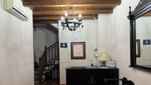 Un espace d’accueil comprenant un bureau, une chaise, un lustre et un escalier menant à une autre pièce.