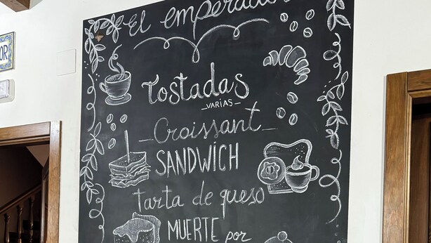 Un tableau noir servant de menu, sur lequel sont énumérés différents plats, et une petite plante en pot posée sur une table.