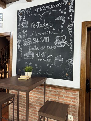 A chalkboard menu with various food items and a small potted plant on a table. - Hostal El Descanso Del Emperador (Jarandilla de la Vera)