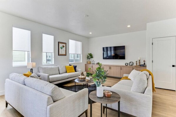 A modern living room with two sofas, a coffee table, and a TV mounted on the wall.