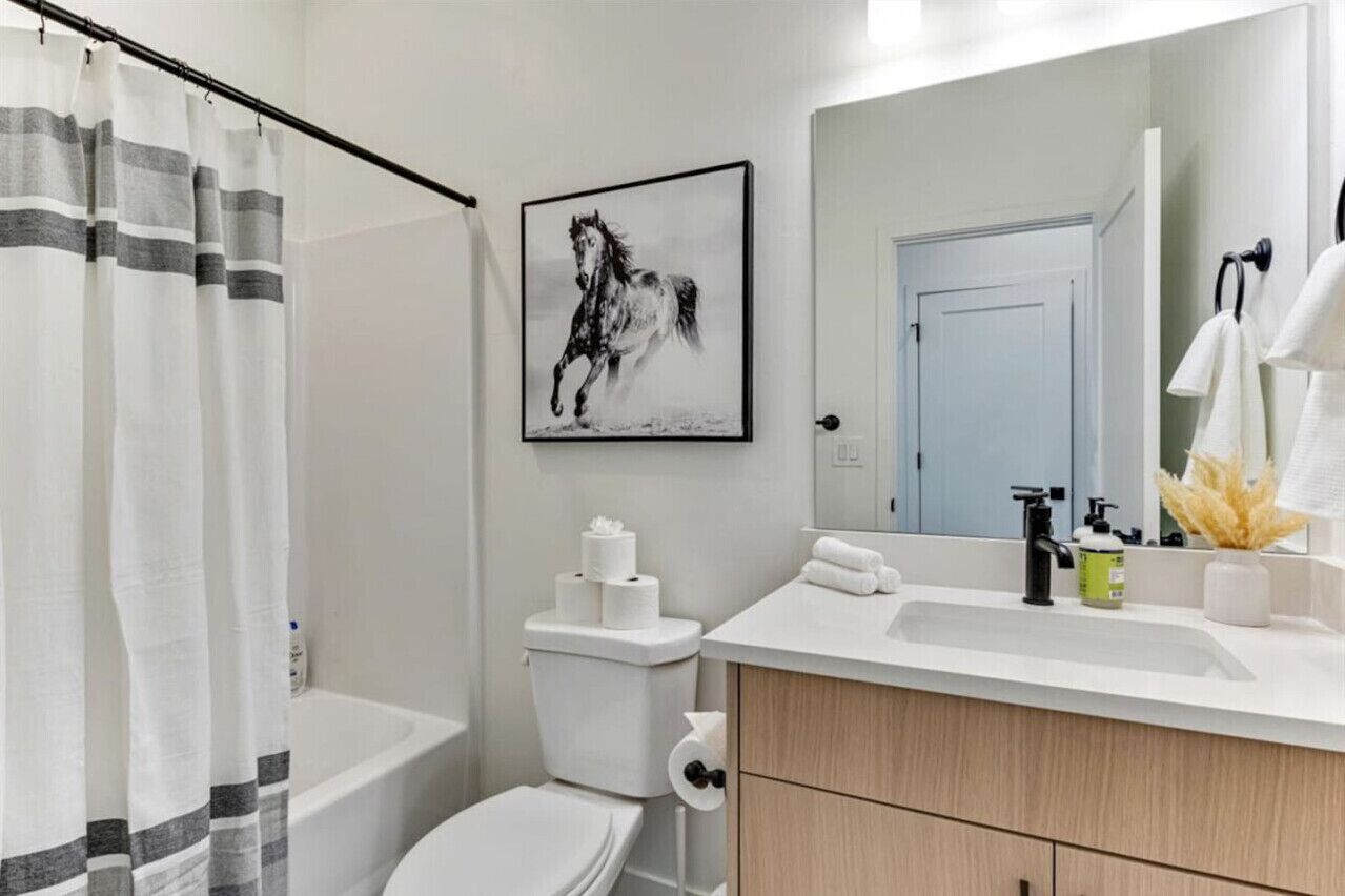 A bathroom with a white toilet, a bathtub, a sink with a mirror, and a towel rack.