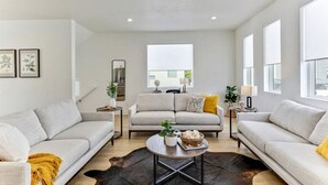 A spacious living room with a neutral color palette, featuring two sofas, a coffee table, and a large window providing natural light. - Pet-Friendly | Silicon Slopes | Garage (American Fork)