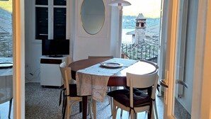 Un coin repas avec une table et des chaises, un téléviseur, un miroir et une vue sur un immeuble par la fenêtre.