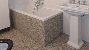 Une salle de bain moderne avec une baignoire sur pieds, un lavabo sur colonne et une fenêtre ornée de barreaux décoratifs.