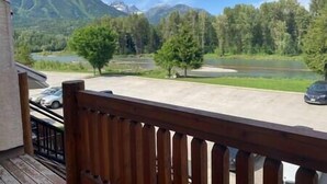Una terraza de madera con vistas a un lago y montañas al fondo.