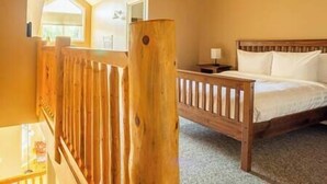 Quarto com cama de madeira, mesa de cabeceira e janela com vista para o exterior.