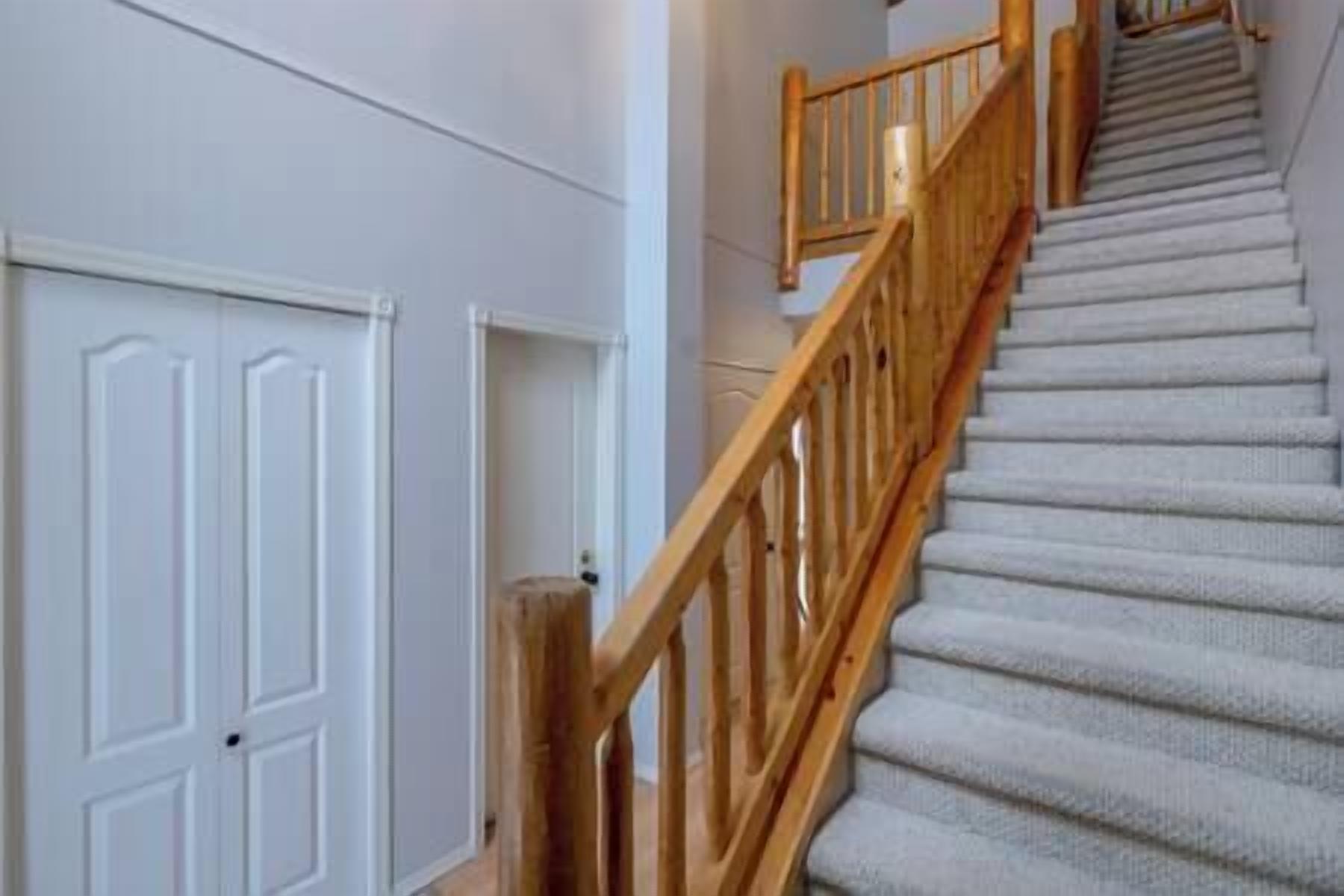 A staircase with wooden railings and carpeted steps.