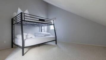 A bunk bed in a room with a sloped ceiling and a plain wall.