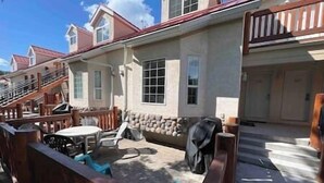 A residential property with a front porch, a covered patio, and a garage. - 3 Story Riverside  Townhome (Fernie)