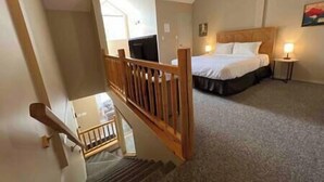 A bedroom with a bed, a bedside table, a nightstand, and a window. - 3 Story Riverside  Townhome (Fernie)