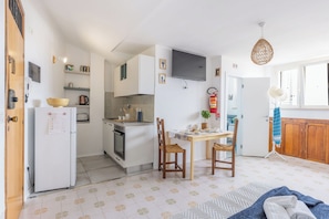 Una cocina compacta con comedor, un televisor sobre la encimera y un extintor en la pared.