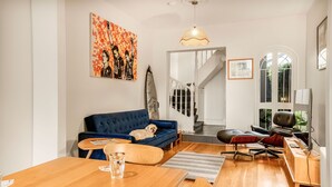 Ein modernes Wohnzimmer mit einem blauen Sofa, einem Holzesstisch und einer Treppe zu einer weiteren Ebene.