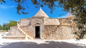 A stone building with a conical roof and a central doorway. - 3985 Tenuta di Uma by Barbarhouse (Carovigno)