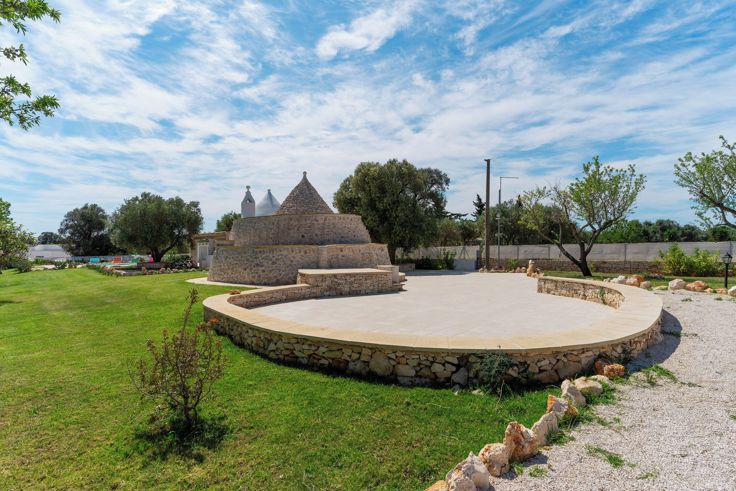 A stone structure with a circular stage and a small pyramid-like building in the background.