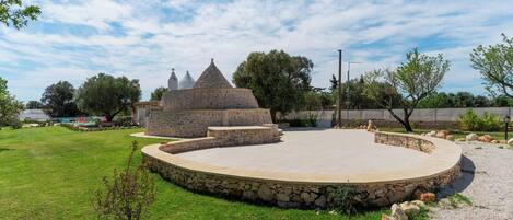 A stone structure with a circular stage and a small pyramid-like building in the background.