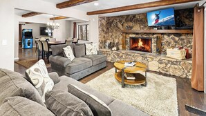 Una sala de estar con chimenea de piedra, televisor y un rincón de estar acogedor.