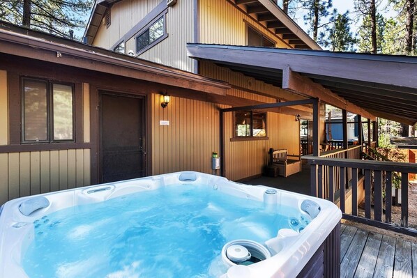 A hot tub on a wooden deck with a house in the background.
