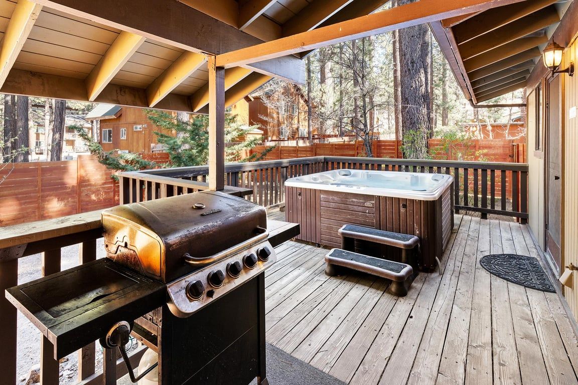 An outdoor deck with a grill, hot tub, and seating area.