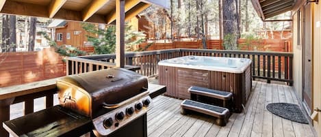 An outdoor deck with a grill, hot tub, and seating area.