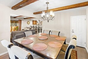 A dining area with a large table, chairs, and a chandelier. - MJ's Hideaway By Destination Big Bear: Walking Distance to Snow Summit!Game Room! Hot Tub! Pet Friendly! Fenced Yard! (Big Bear Lake)
