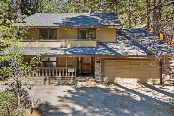 A two-story house with a garage, surrounded by trees.