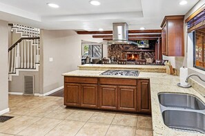 A kitchen with a central island, built-in cabinets, a gas stove, and a fireplace.