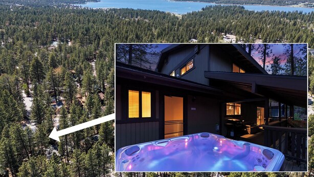 Una cabaña con jacuzzi en la terraza, rodeada de un bosque y un lago.