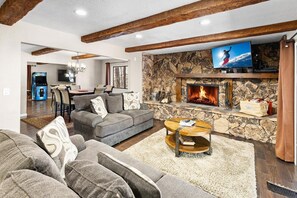 A living room with a stone fireplace, a television mounted above it, and a sofa set.