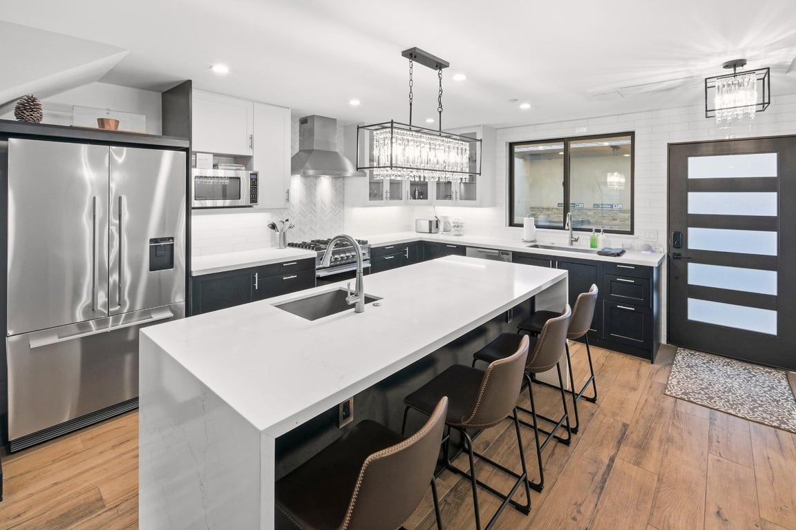 A modern kitchen with a central island, stainless steel appliances, and bar stools.