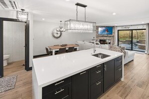 A modern kitchen with a large island, a dining area, and a living space with a fireplace.