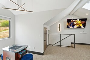 Ein Zimmer mit Deckenventilator, einem an der Wand befestigten Fernseher, einem Tischtennisschlag und Blick ins Freie durch ein Fenster.