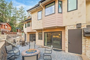 A two-story house with a patio area featuring outdoor seating and a fire pit. - Clip In and Ride Straight Onto Chair 9 at Bear Mountain! Private HOT TUB! Air Conditioning! Pickle Ball Court! EV Charger! (Big Bear Lake)