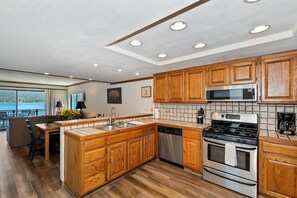 Une cuisine moderne avec des meubles en bois, des appareils en acier inoxydable et une vue sur l’extérieur.
